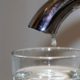 Close up image of a tap with a drop of water falling into a glass